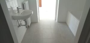 Neues Bad mit Waschbecken, weißen Wandfliesen und Fliesenboden
