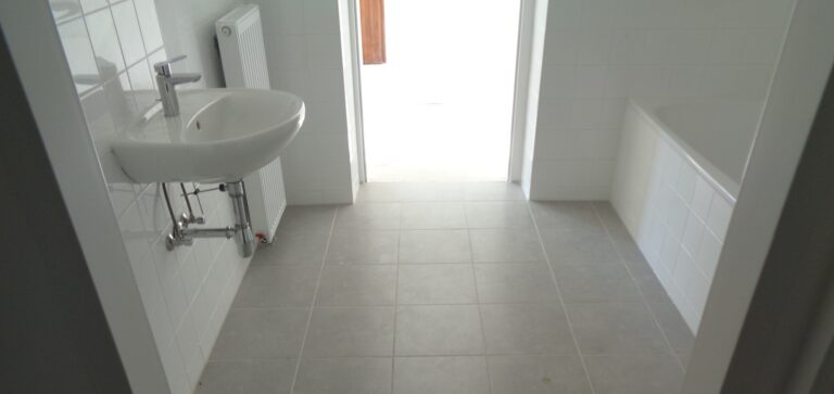 Neues Bad mit Waschbecken, weißen Wandfliesen und Fliesenboden