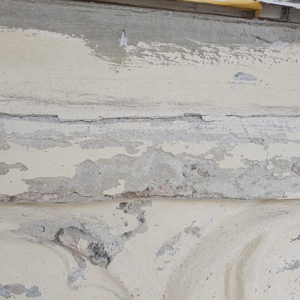Abblätternde Beschichtung an der Fassade vor der Sanierung