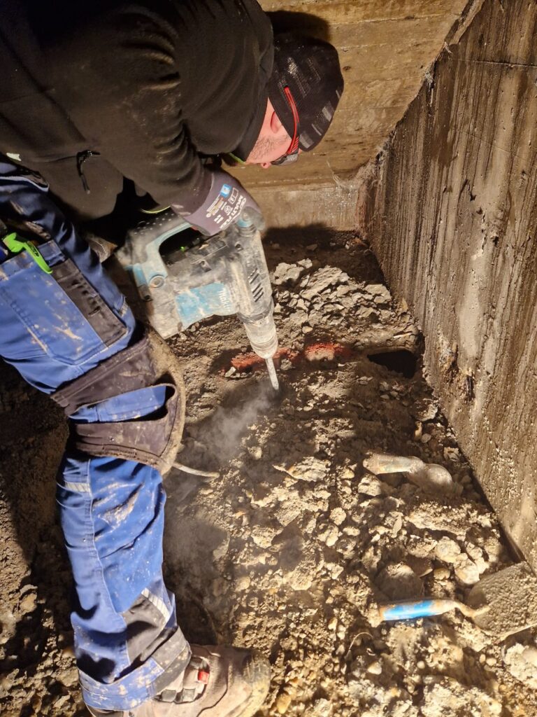 emasan-Mitarbeiter stemmt Beton an einer engen Stelle von Hand auf