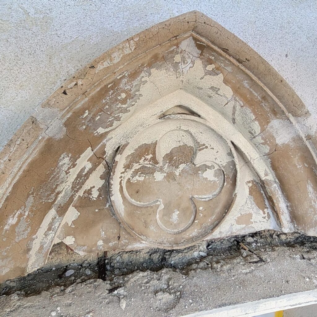 Giebelfeld mit Ornament und abgeplatztem Putz vor der Sanierung