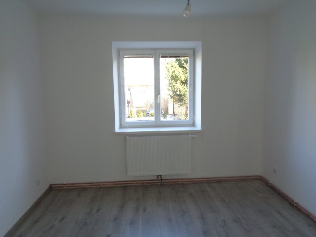 Zimmer mit neuem Bodenbelag und weißen Wänden nach der Sanierung