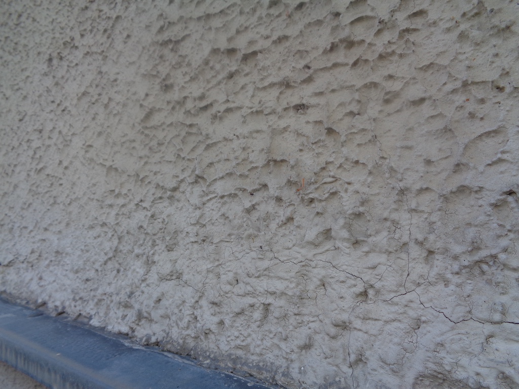 Strukturierte Putzfläche mit feinen Rissen an der Fassade