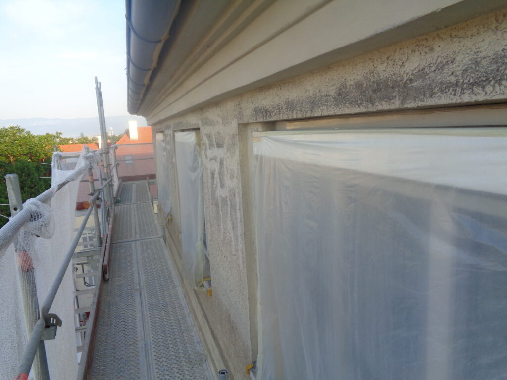 Gesims mit verschmutzter Putzfläche an der Fassade