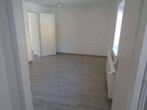 Helles Zimmer mit neuem Bodenbelag, weißen Wänden und Türen nach der Sanierung