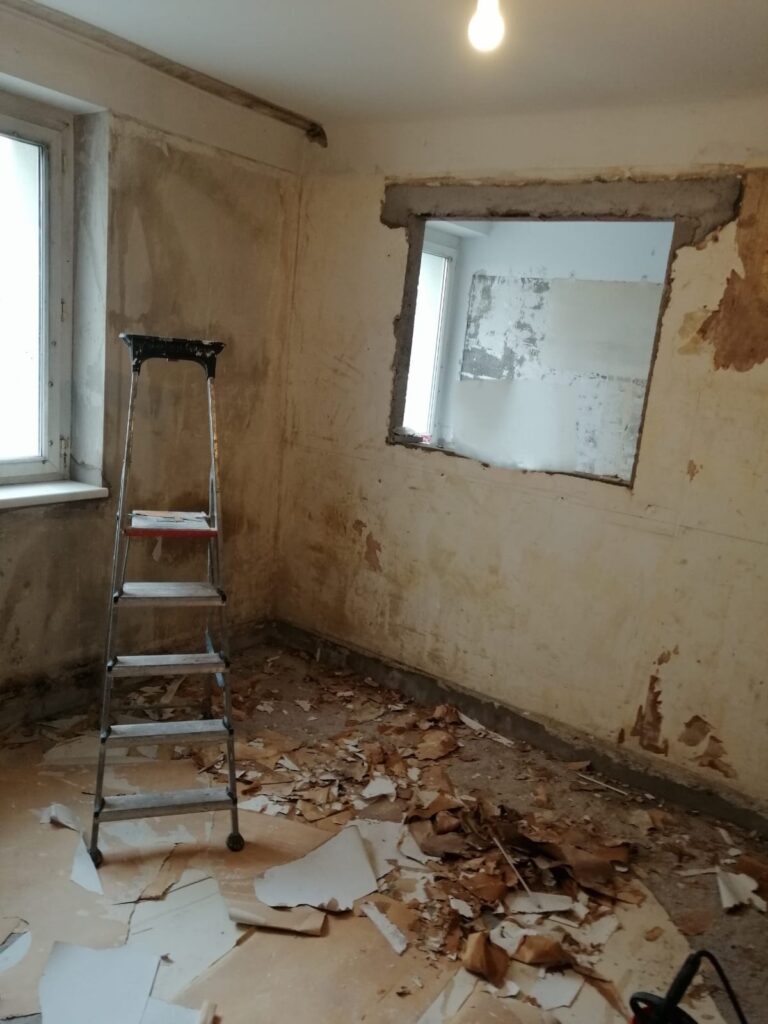 Zimmer mit Durchreiche und Leiter vor der Sanierung